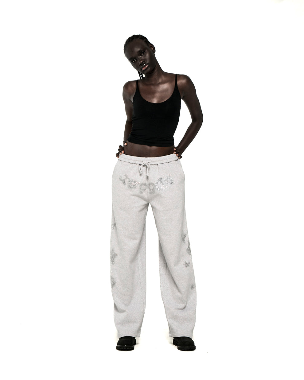 Model wearing light grey RHINESTONE BELUGA V2 WIDE LEG SWEATPANTS with 'SP5DER' text and star designs.