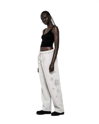 Model in light grey wide-leg sweatpants with rhinestone SP5DER text, '5', and star designs.