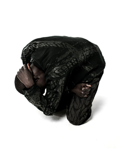 Black waffle knit thermal with ribbed collar, hem, and cuffs, featuring an all-over tire track print.