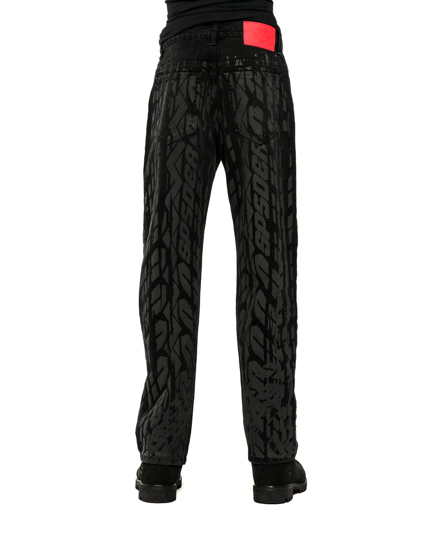 Black burnout denim pants with all-over tire track design and red branded leather back patch.