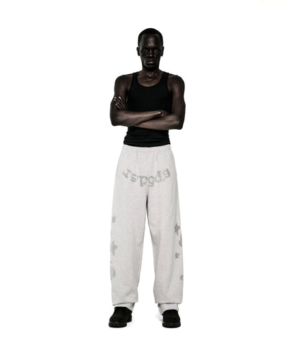 Model wearing light grey rhinestone-embellished wide-leg sweatpants with "SP5DER" text, "5", and star designs.