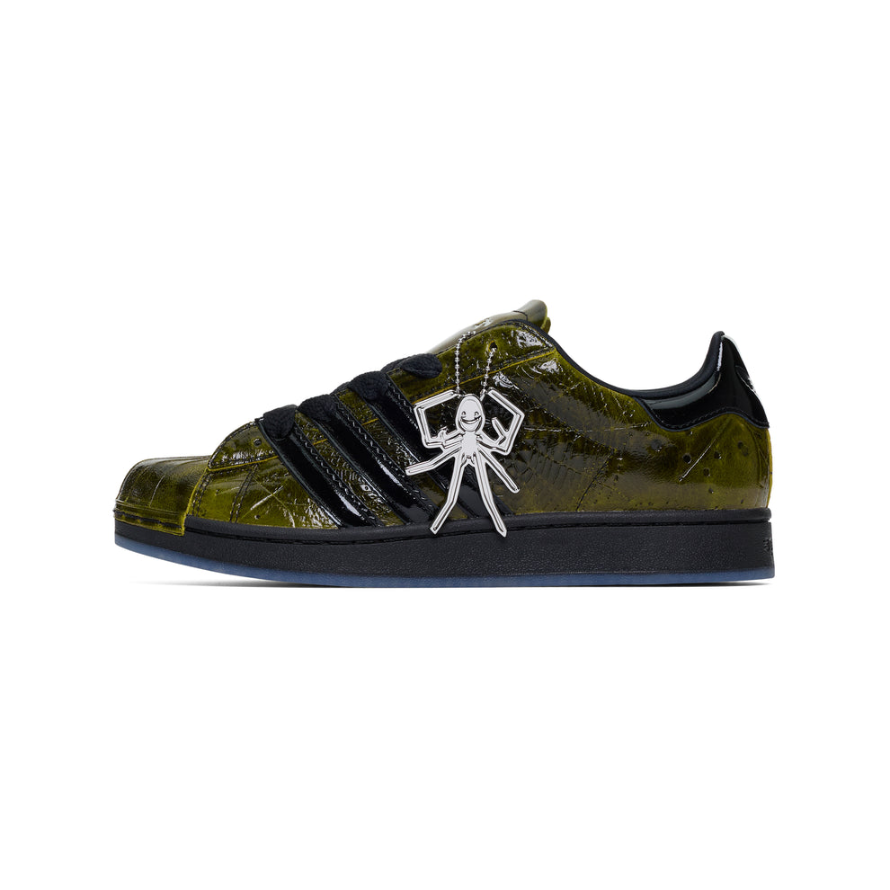 SP5DER x ADIDAS SUPERSTAR sneaker with glossy cracked olive patent leather, black stripes, and a silver spider charm.