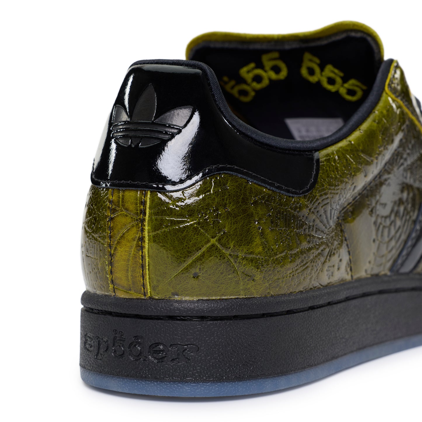 SP5DER x ADIDAS SUPERSTAR in glossy cracked olive patent leather with black accents, spider charm, and "555" detail.