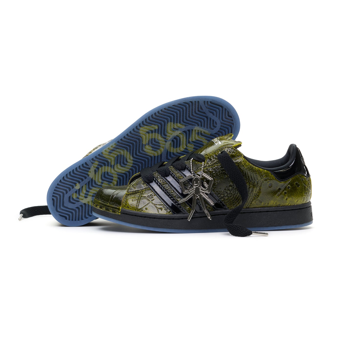 SP5DER x ADIDAS SUPERSTAR in glossy cracked olive patent leather with black stripes, spider charm, and blue translucent sole.