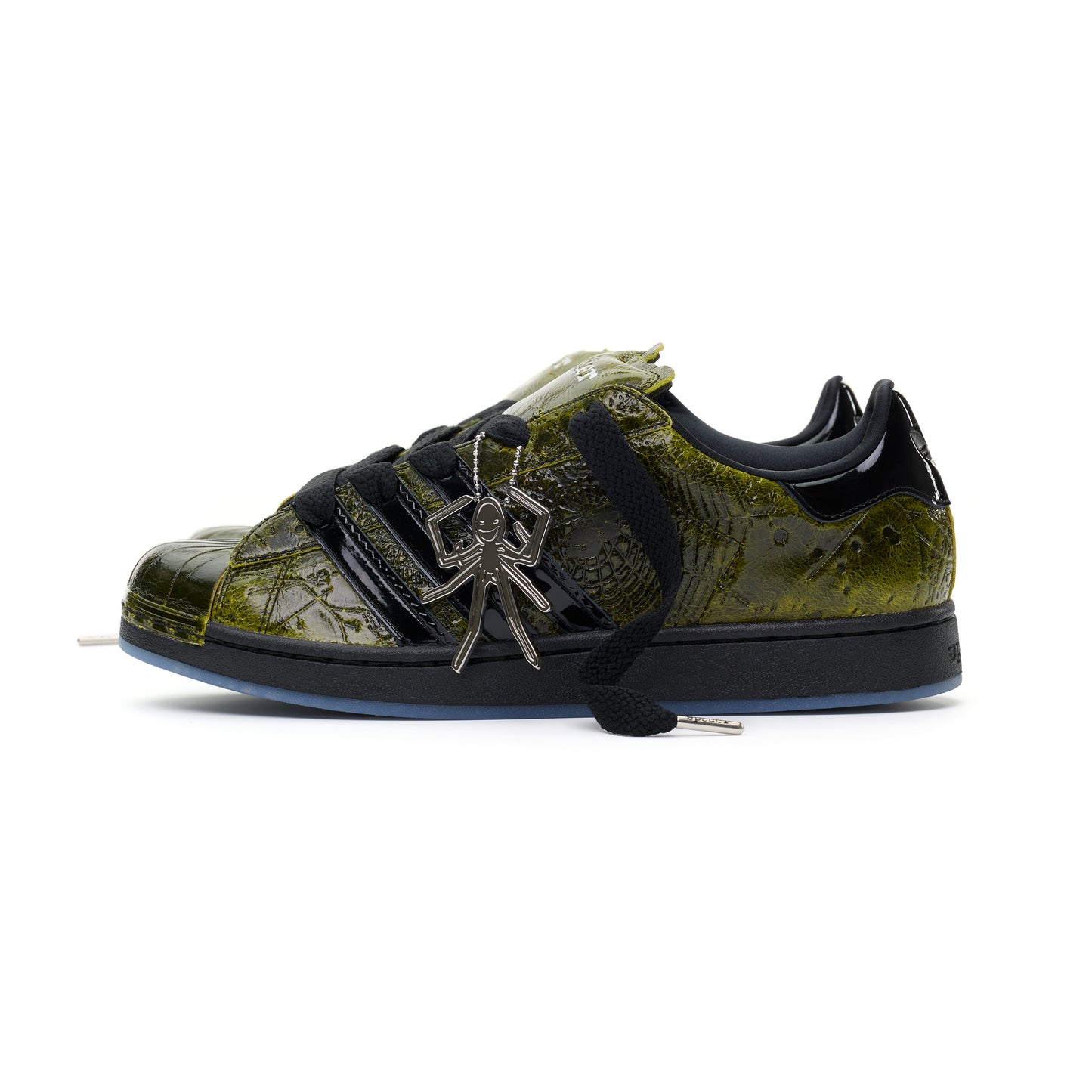 SP5DER x ADIDAS SUPERSTAR in glossy cracked olive patent leather with black laces and a silver spider charm.