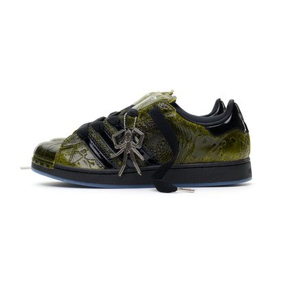 SP5DER x ADIDAS SUPERSTAR in glossy cracked olive patent leather with black laces and a silver spider charm.