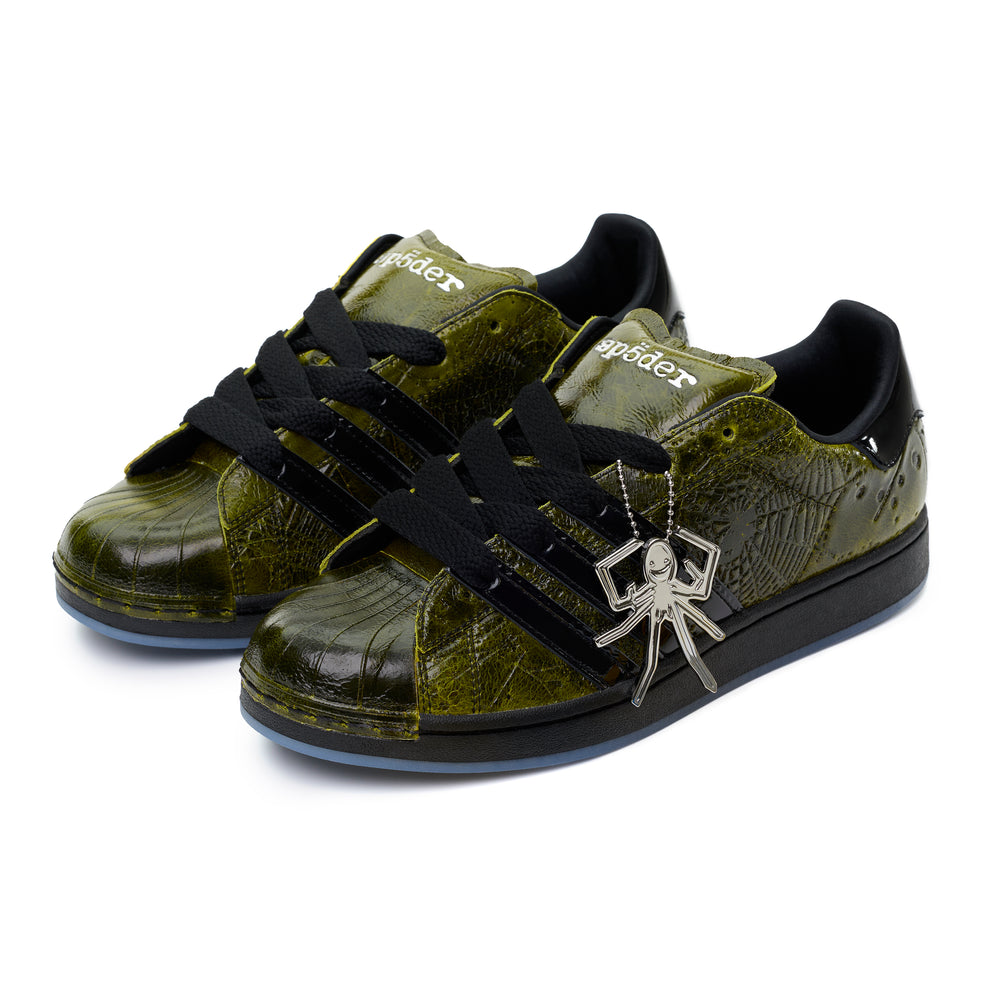 SP5DER x ADIDAS SUPERSTAR sneakers with glossy cracked olive patent leather, black laces, spider charm, and black stripes.