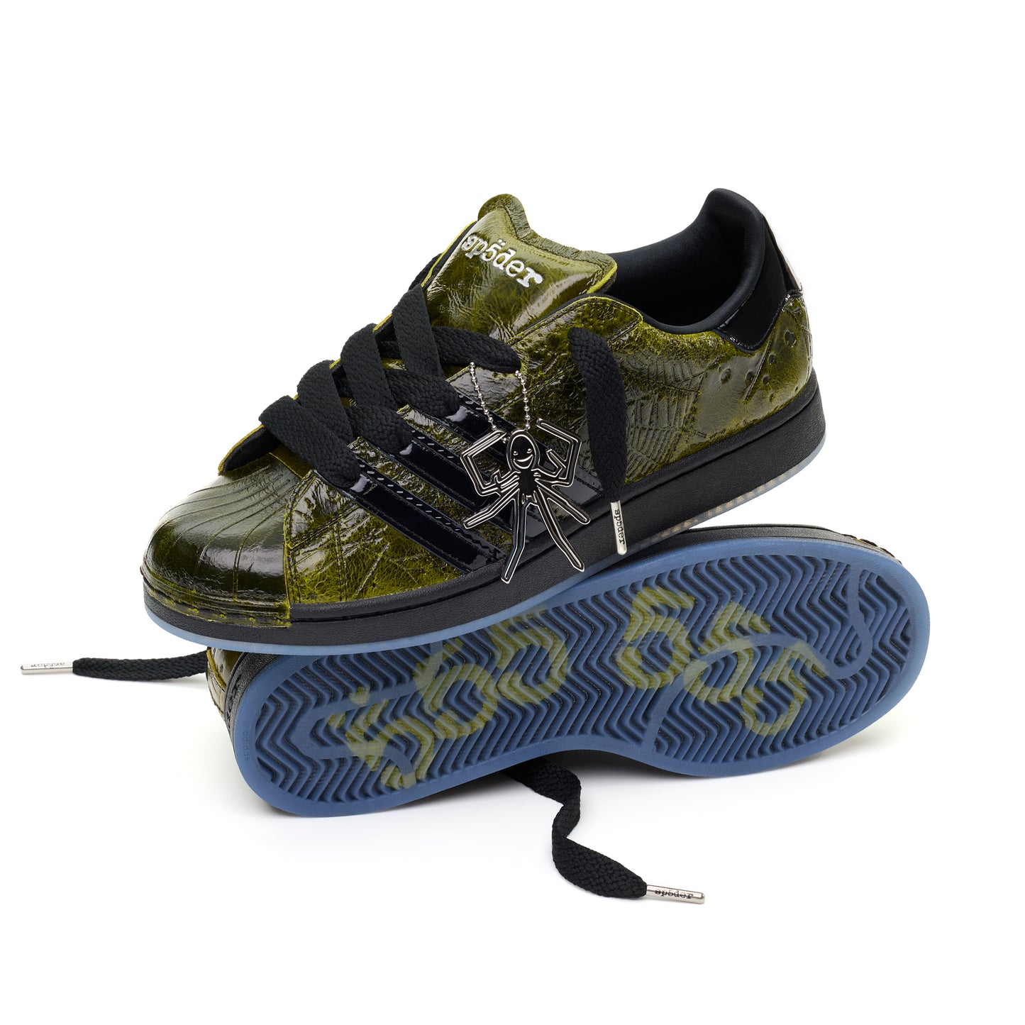 SP5DER x ADIDAS SUPERSTAR in glossy cracked olive patent leather with black stripes, laces, and a spider charm.