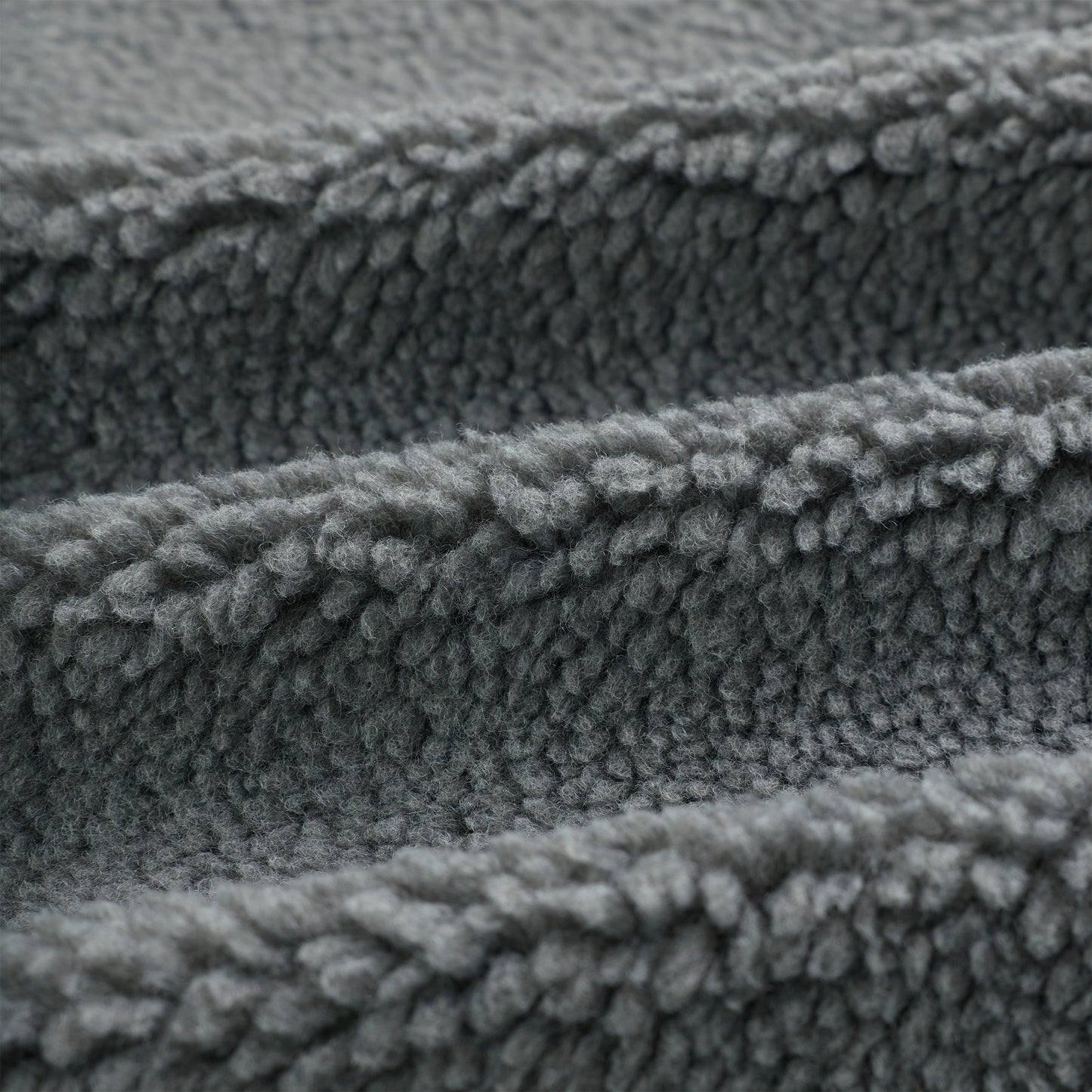 Close-up of soft, textured gray sherpa fleece fabric, folded in waves.