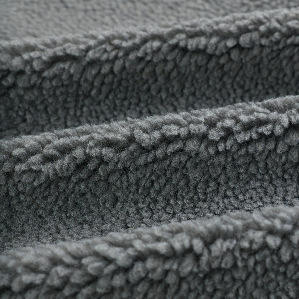 Close-up of soft, textured gray sherpa fleece fabric, folded in waves.