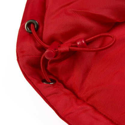 Close-up of a red poly-fill puffer jacket hem with internal drawstring and black grommets.