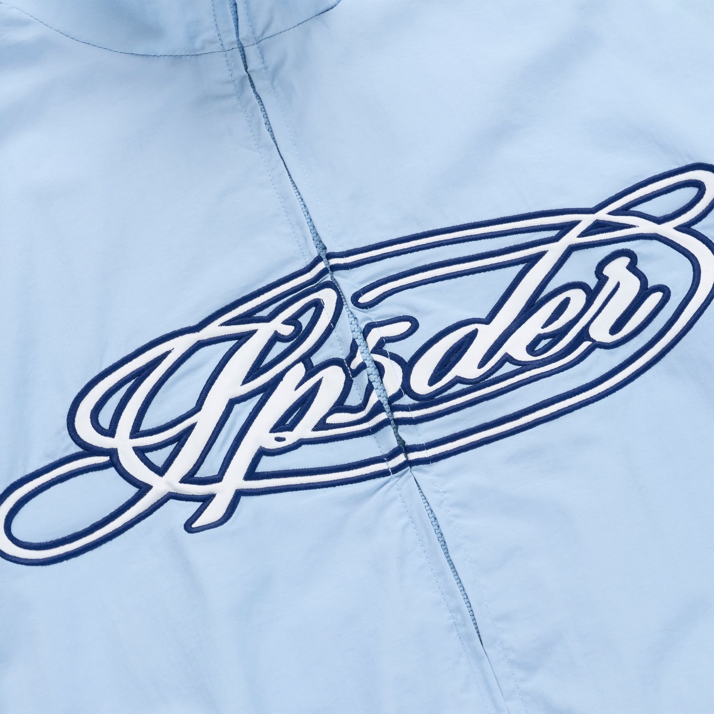 Light blue nylon track jacket with a white and navy embroidered "Upsider" script logo on the chest.