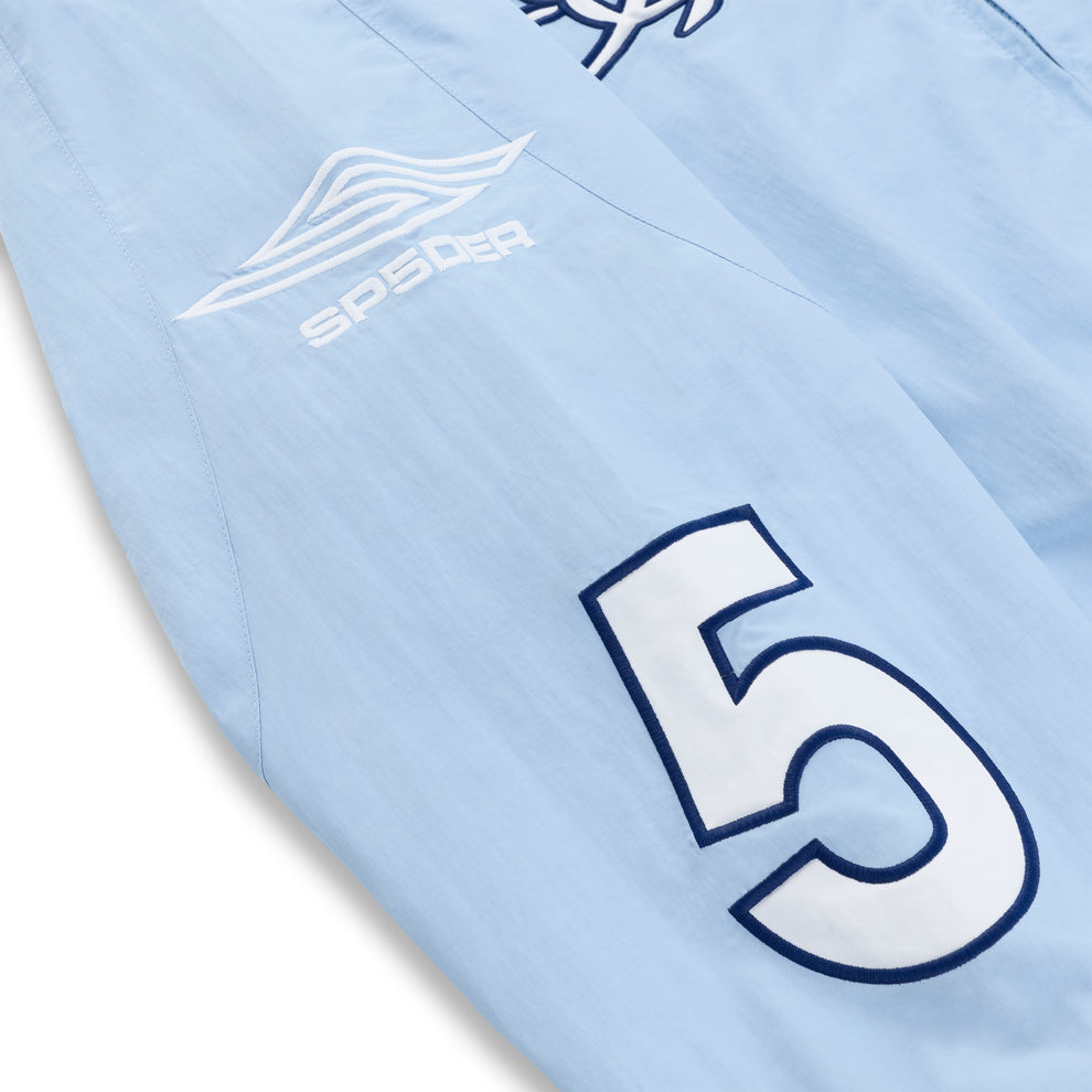Light blue nylon track jacket sleeve with white "SP5DER" logo and large navy "5" graphic.