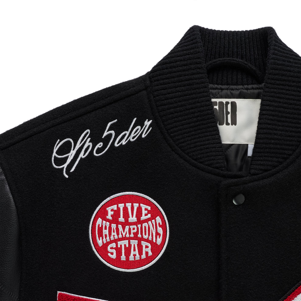 Black wool varsity jacket with leather sleeves, embroidered patches, and ribbed collar.