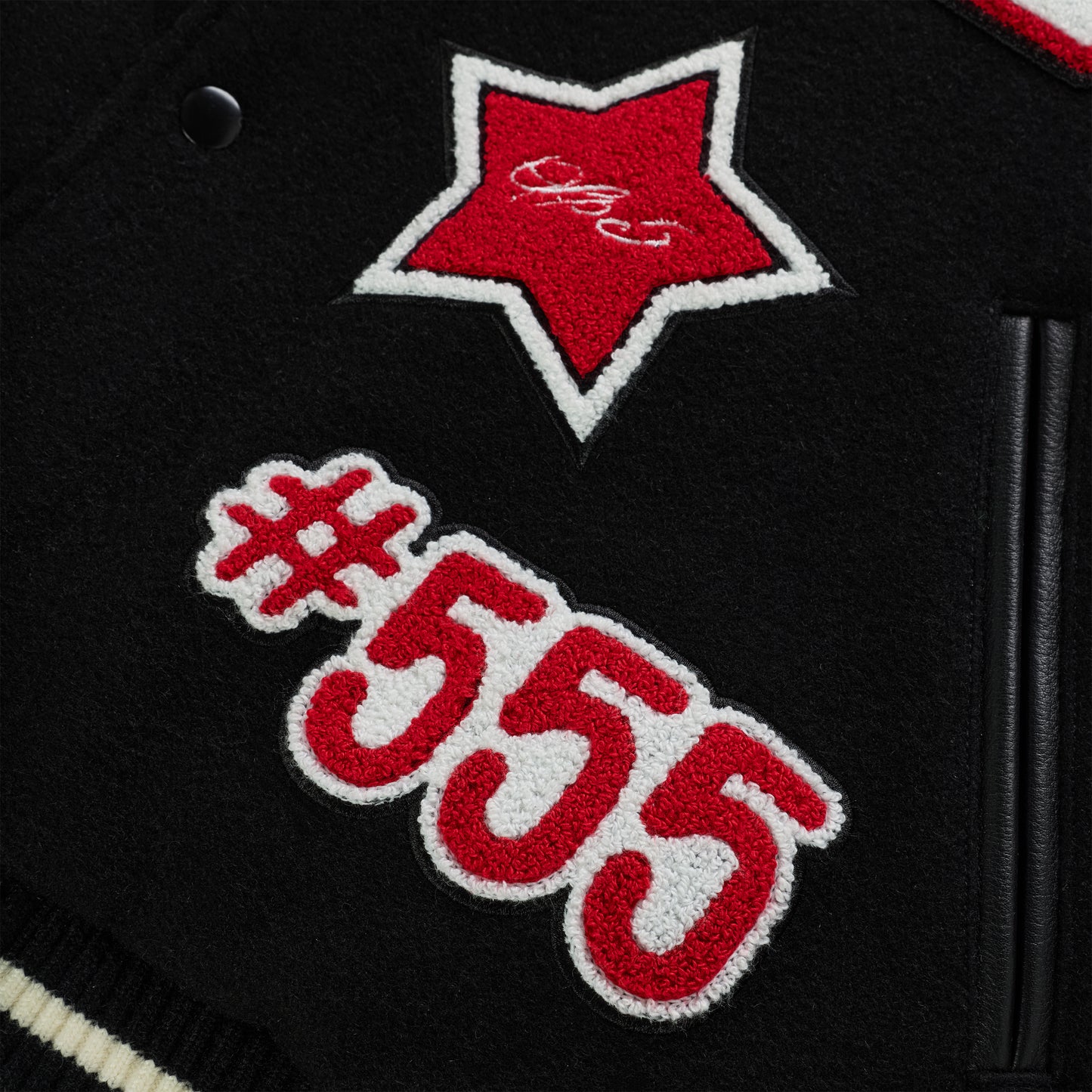 Black wool varsity jacket with red and white embroidered star and "#555" patches, leather trim.