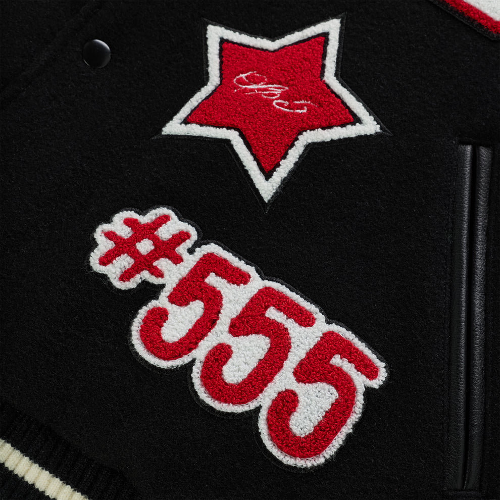 Black wool varsity jacket with red and white embroidered star and "#555" patches, leather trim.