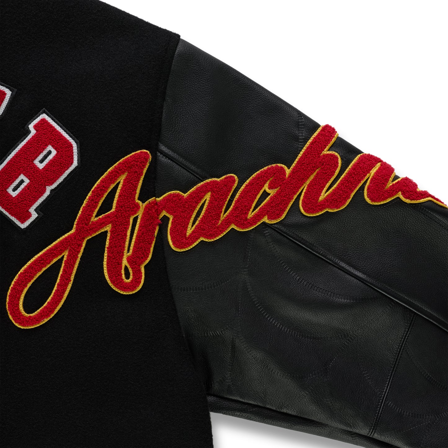 Black wool varsity jacket with contrasting leather sleeves, debossed web design, and red embroidered script.