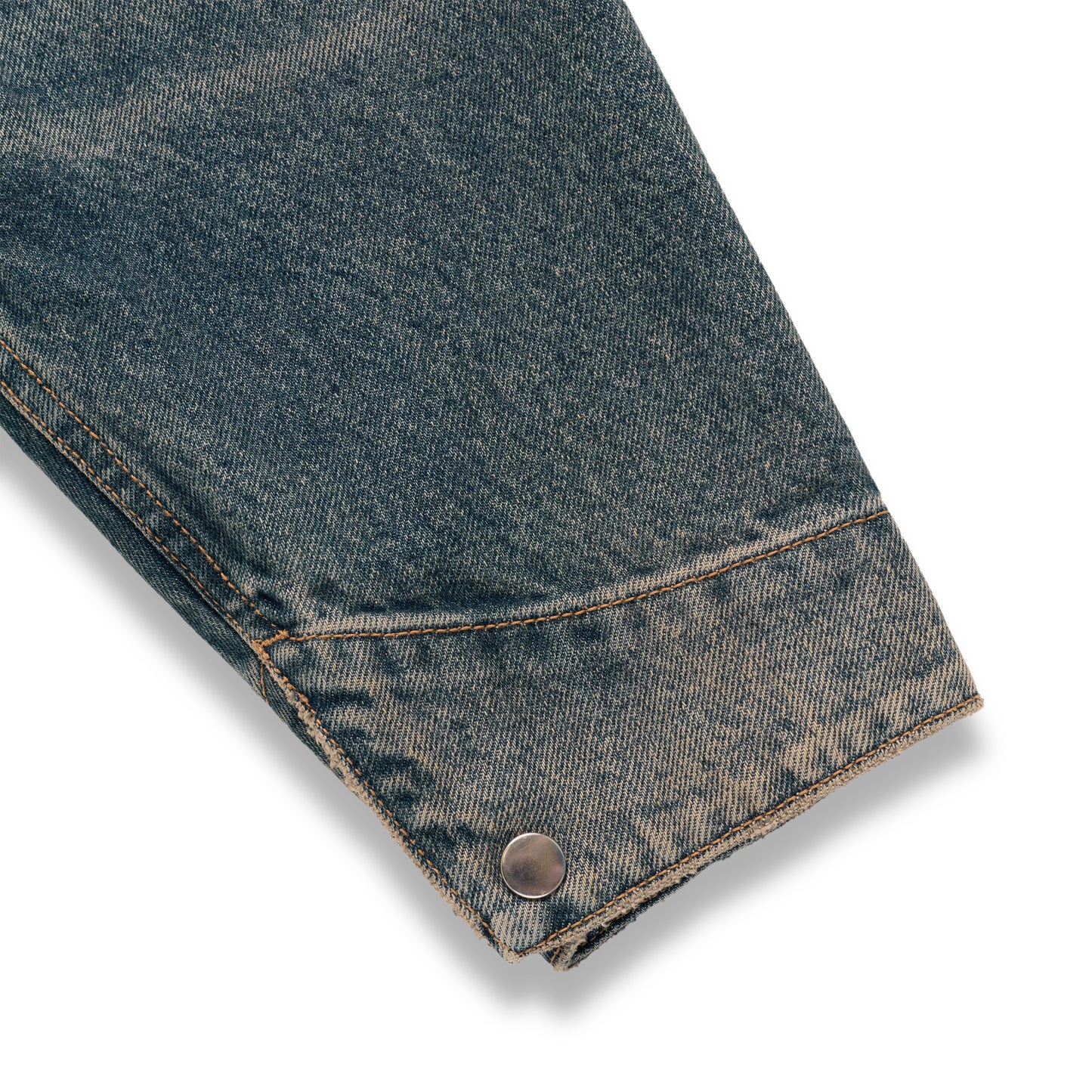 Worn blue denim work jacket sleeve with a single silver snap button cuff and contrast stitching.