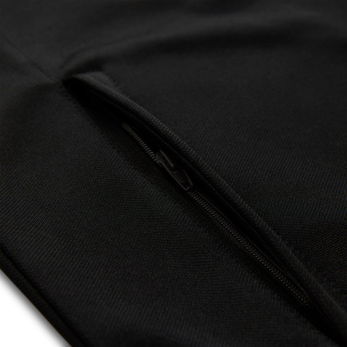 Close-up of a black athletic polyester track jacket with a zippered side pocket.