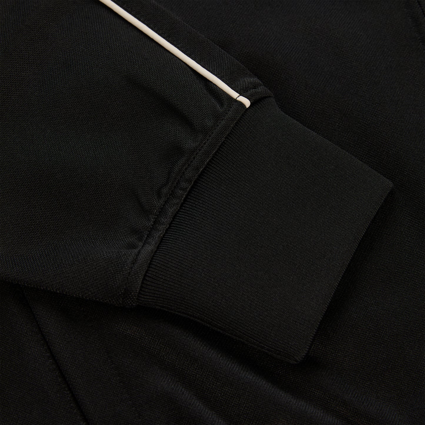 Black polyester Atlanta Track Jacket sleeve with white piping and ribbed cuff.