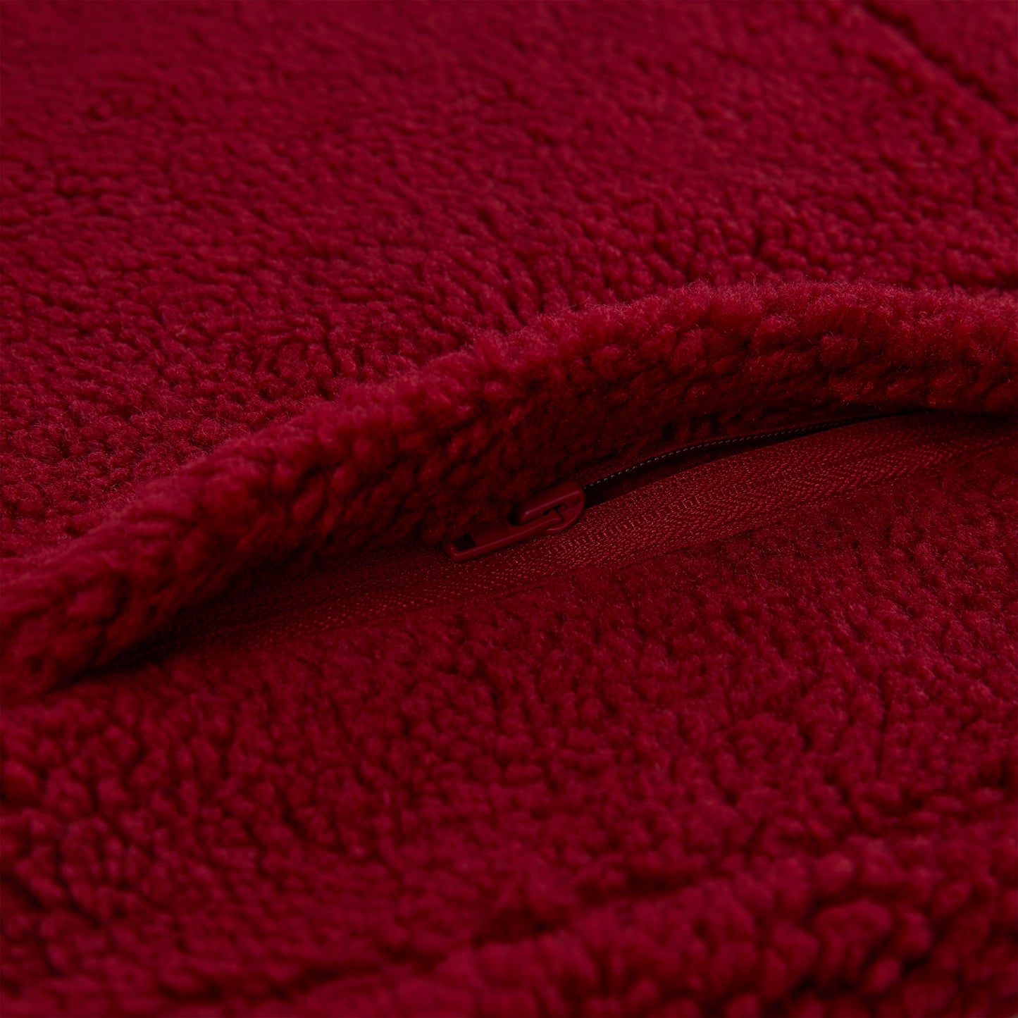 Close-up of a red teddy sherpa fleece zip-up jacket with a matching zipper.