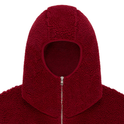 Close-up of a red sherpa fleece hooded jacket with a narrow front opening and silver zip closure.