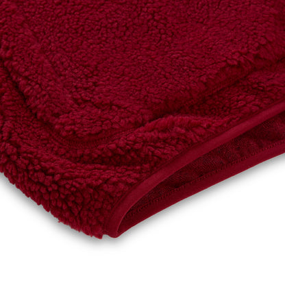 Close-up of a dark red teddy sherpa fleece zip-up jacket with a rubberized logo patch.