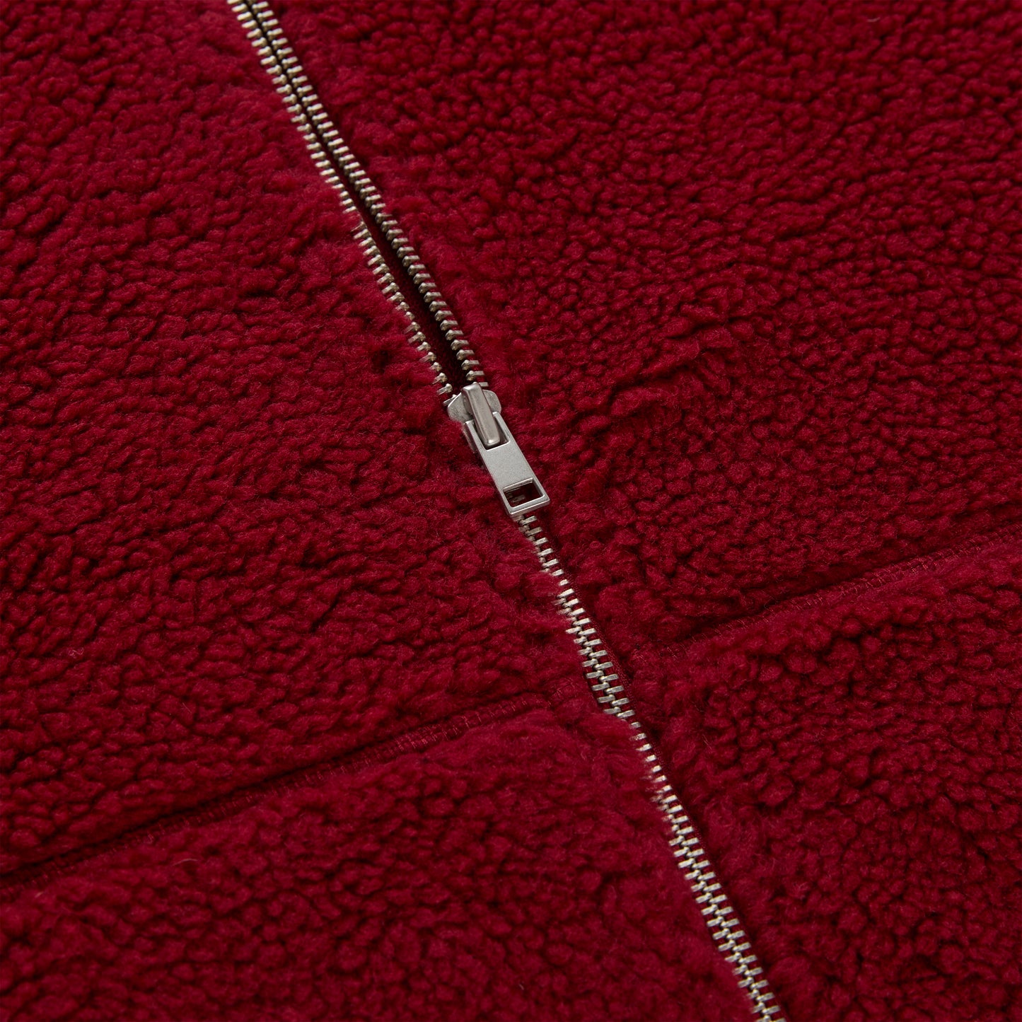 Close-up of a red teddy sherpa fleece zip-up jacket with a silver zipper.