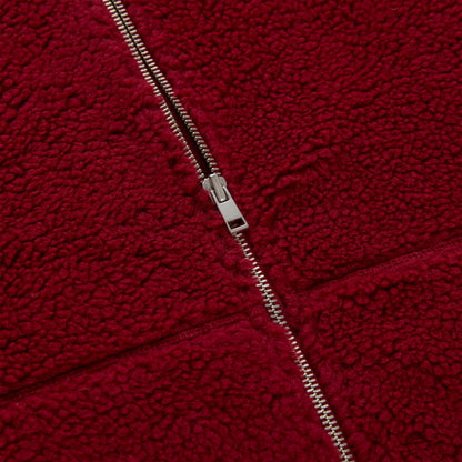 Close-up of a red teddy sherpa fleece zip-up jacket with a silver zipper.