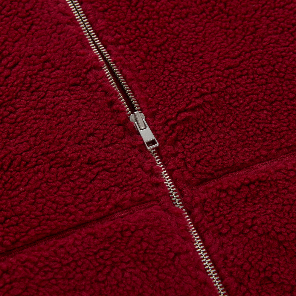Close-up of a red teddy sherpa fleece zip-up jacket with a silver zipper.
