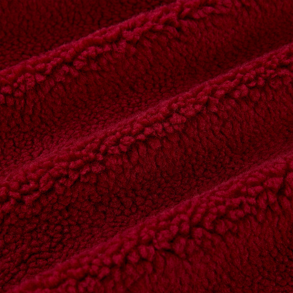 Close-up of plush red teddy sherpa fleece fabric with soft, textured loops and gentle folds.
