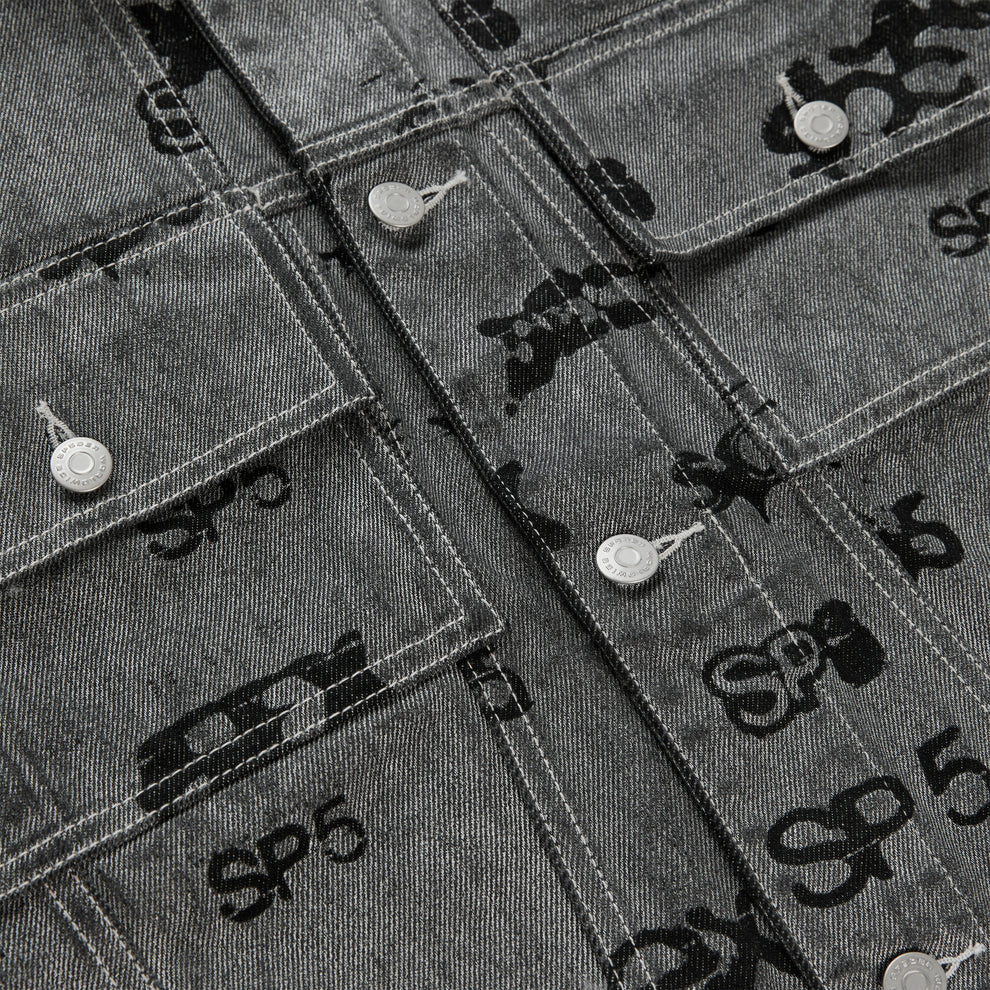 Gray denim trucker jacket with all-over black foil print, silver buttons, and red contrast stitching.
