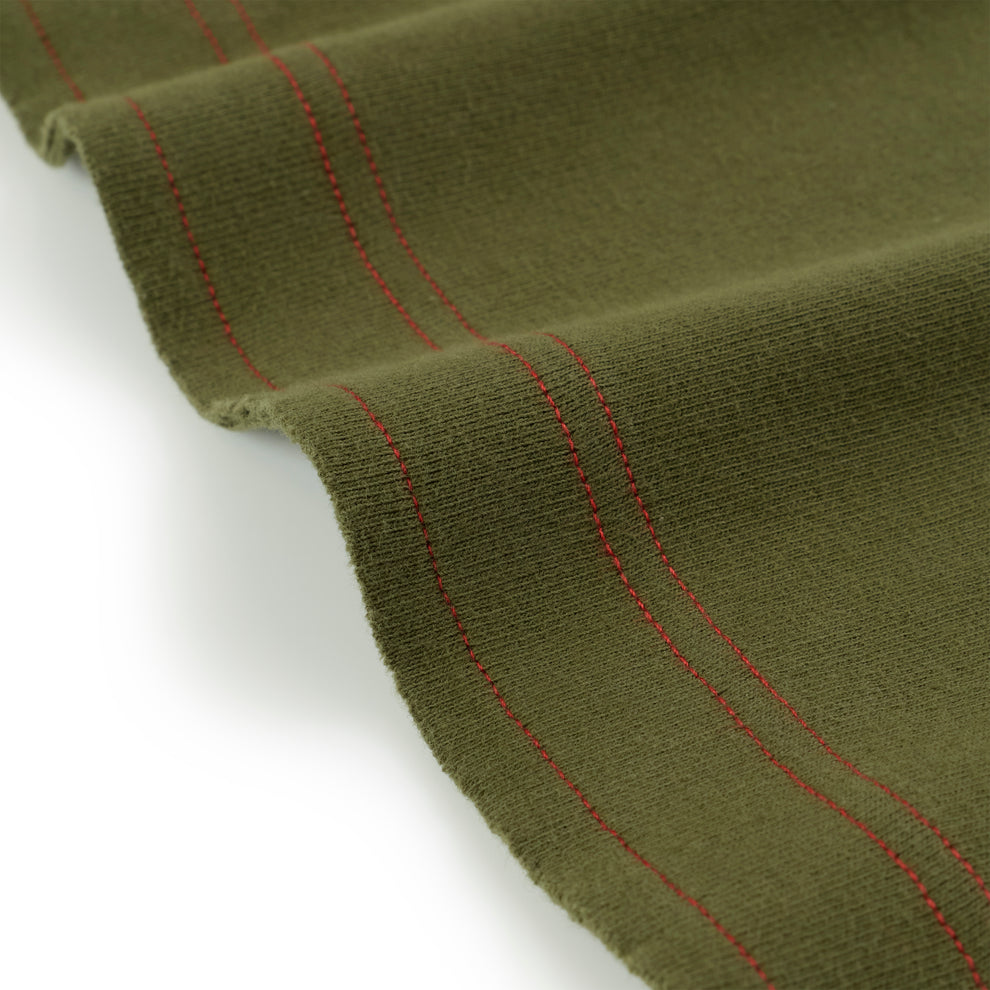Olive green knit fabric with red stitching detail, folded on white background.