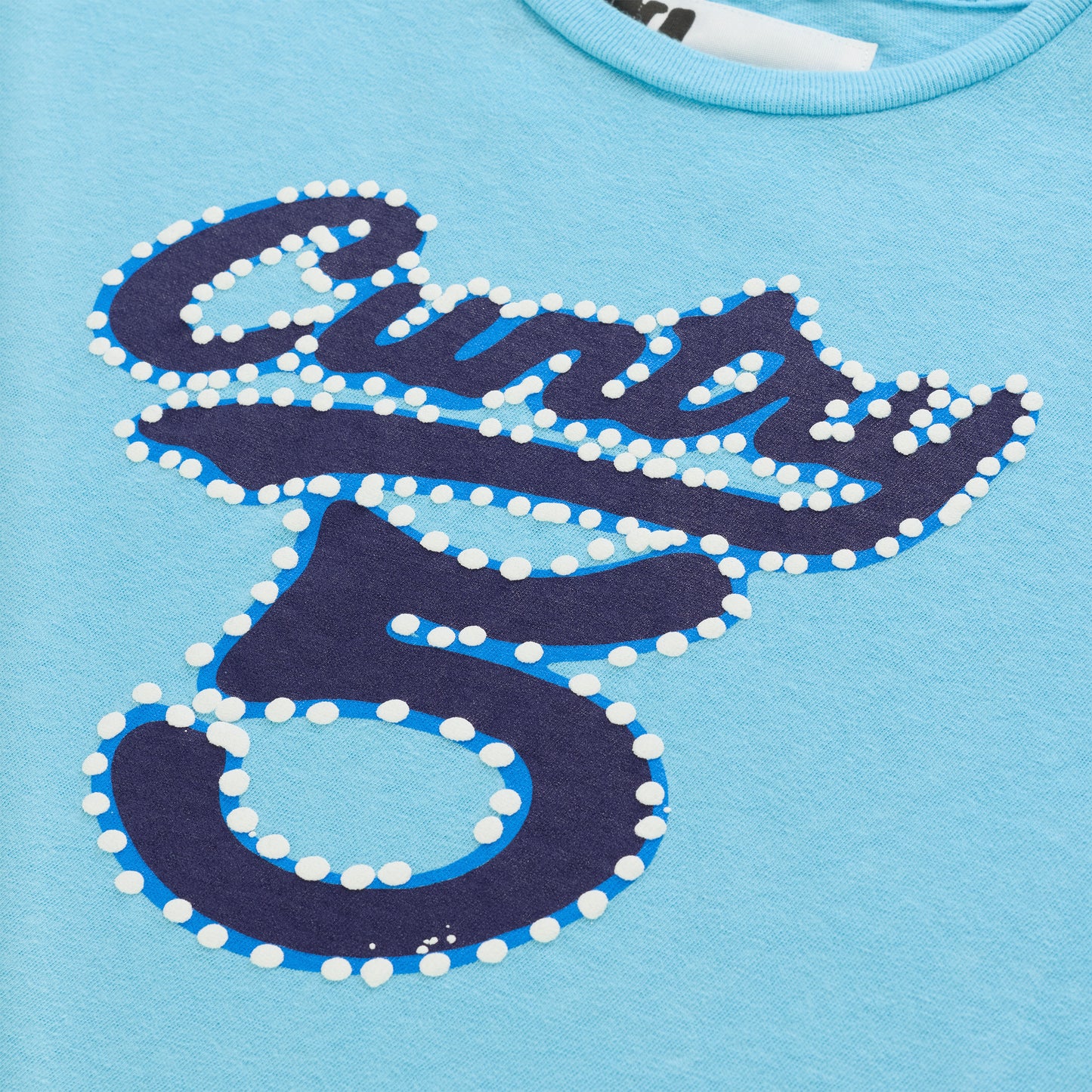Light blue cotton/spandex cropped tee with "CUNTRY 5" graphic in dark blue with white raised dots.