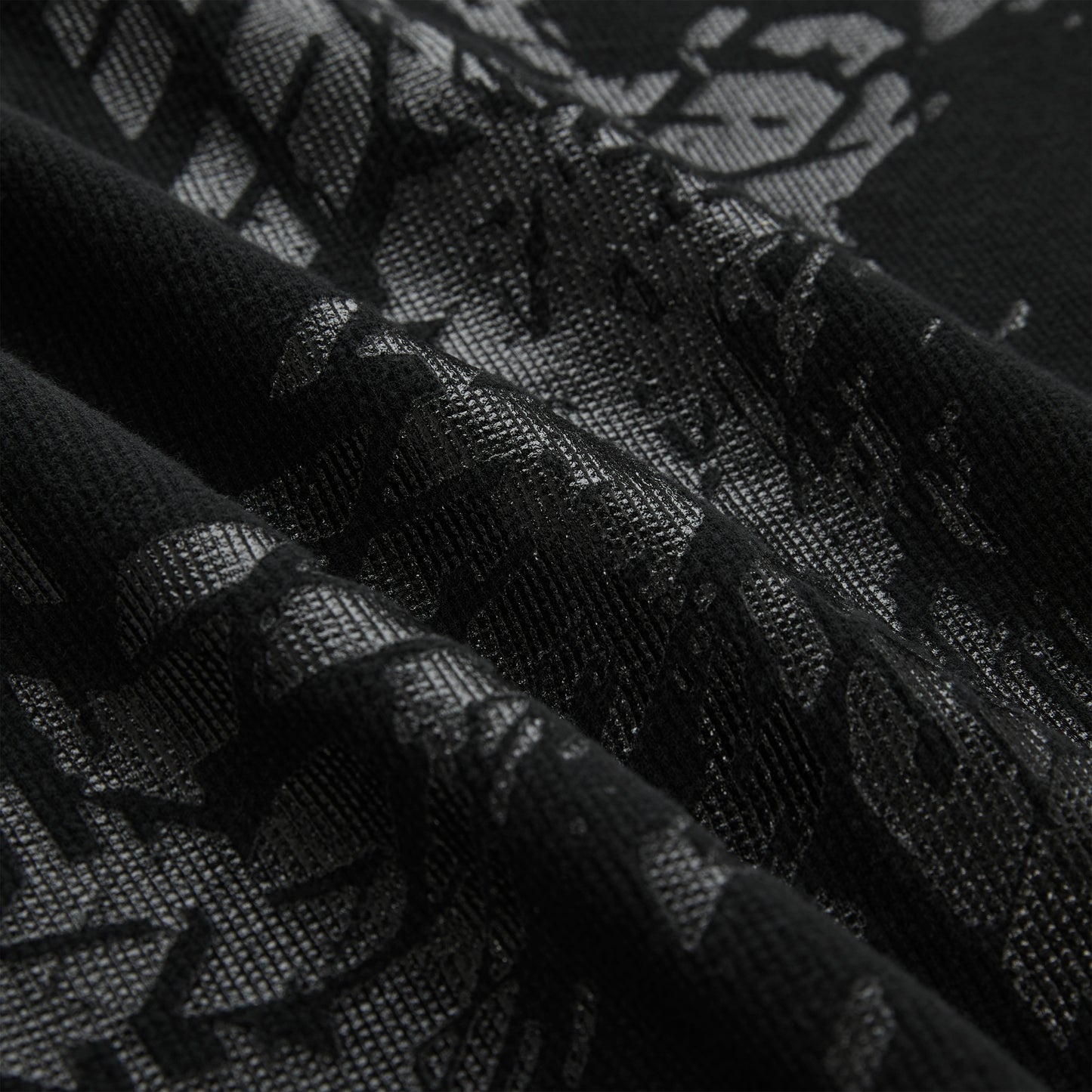Close-up of a black waffle knit thermal with an all-over tire track print.