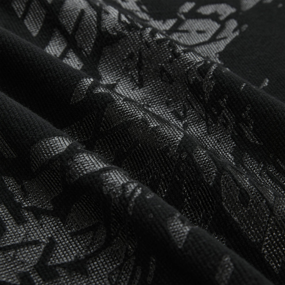 Close-up of a black waffle knit thermal with an all-over tire track print.