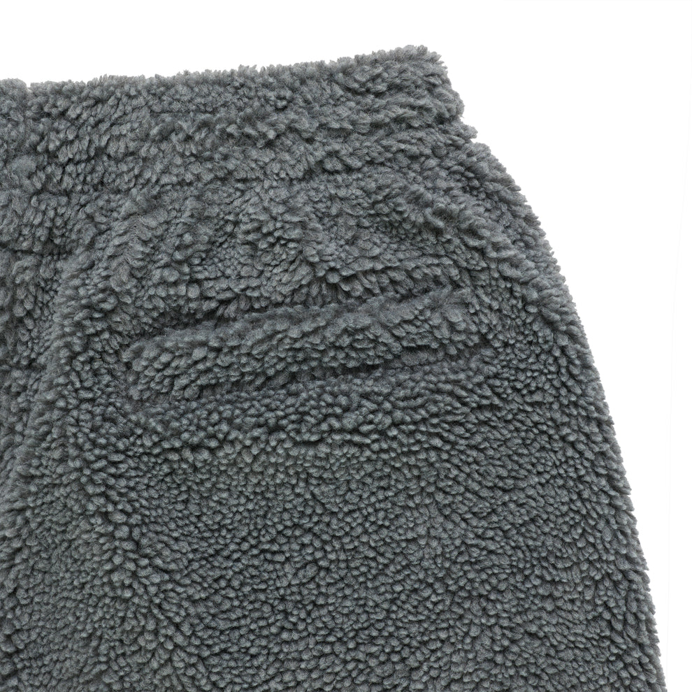 Close-up of gray sherpa fleece pant with textured material and pocket detail.