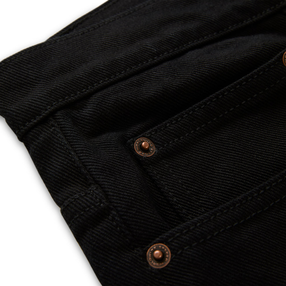Black denim pant with custom branded copper hardware and belt loops.