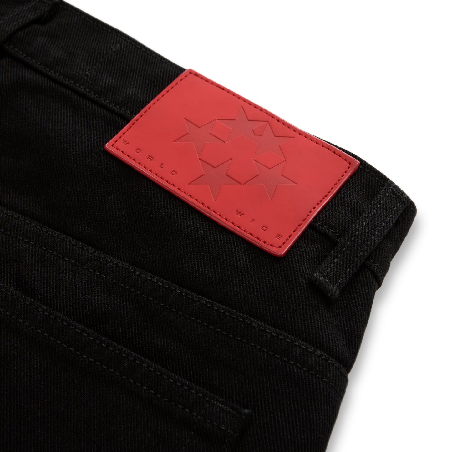 Black denim jeans with a red leather back patch featuring embossed stars and "WORLD WIDE" branding.
