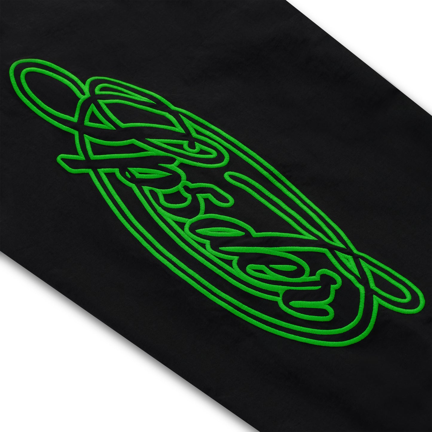 Black nylon track pant with vibrant green embroidered script graphic.