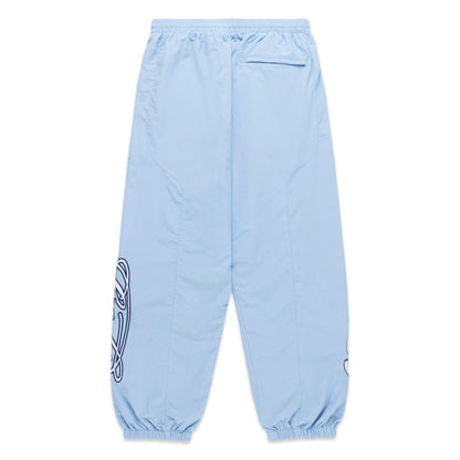 Light blue nylon track pants with paneled construction, elasticized cuffs, and embroidered graphic detailing.