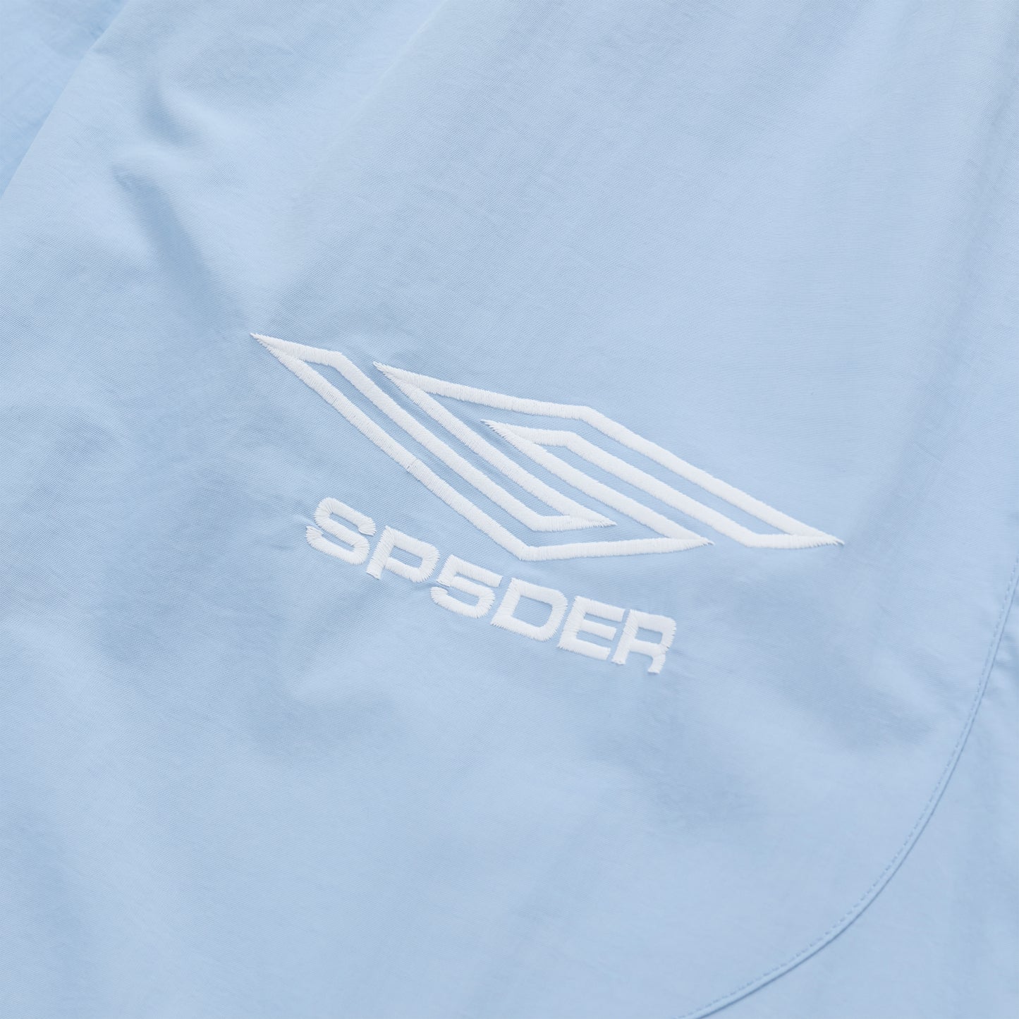 Light blue nylon track pant with white embroidered SP5DER logo and graphic.