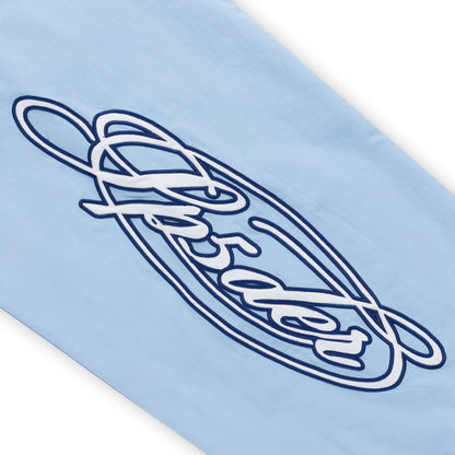 Light blue nylon track pant with embroidered white and navy script graphic.