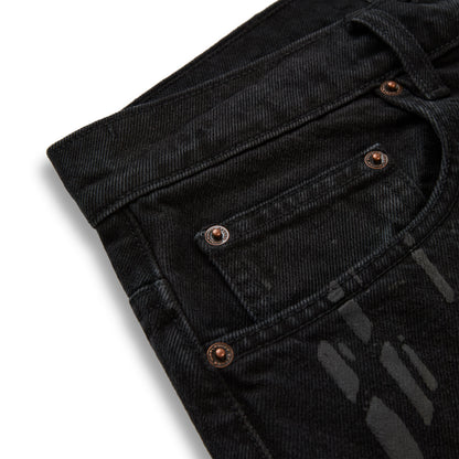 Black denim pants with all-over tire track design and custom branded copper hardware.