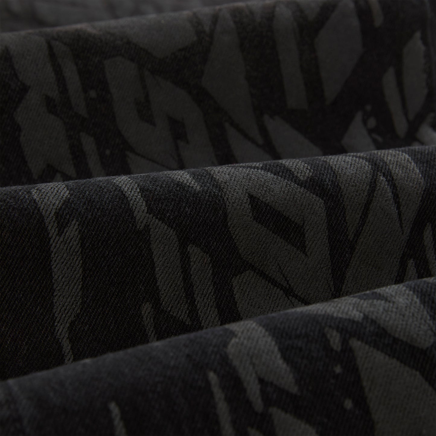 Close-up of black denim with a subtle all-over tire track design.