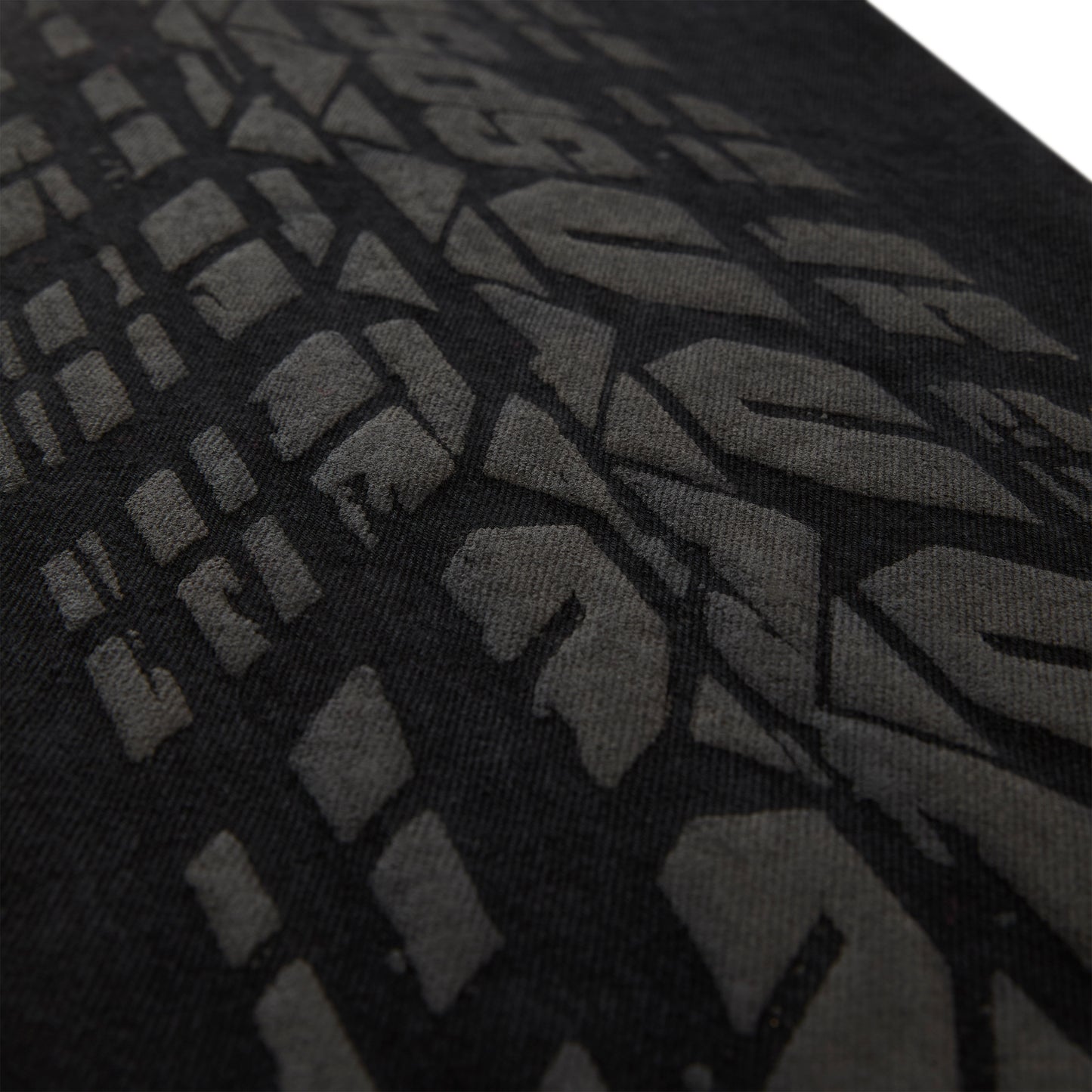 Close-up of black denim with an all-over dark gray tire track design.