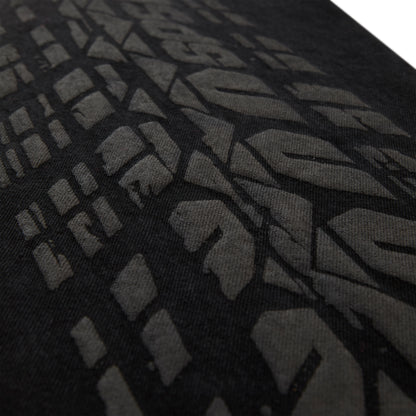 Close-up of black denim with an all-over dark gray tire track design.