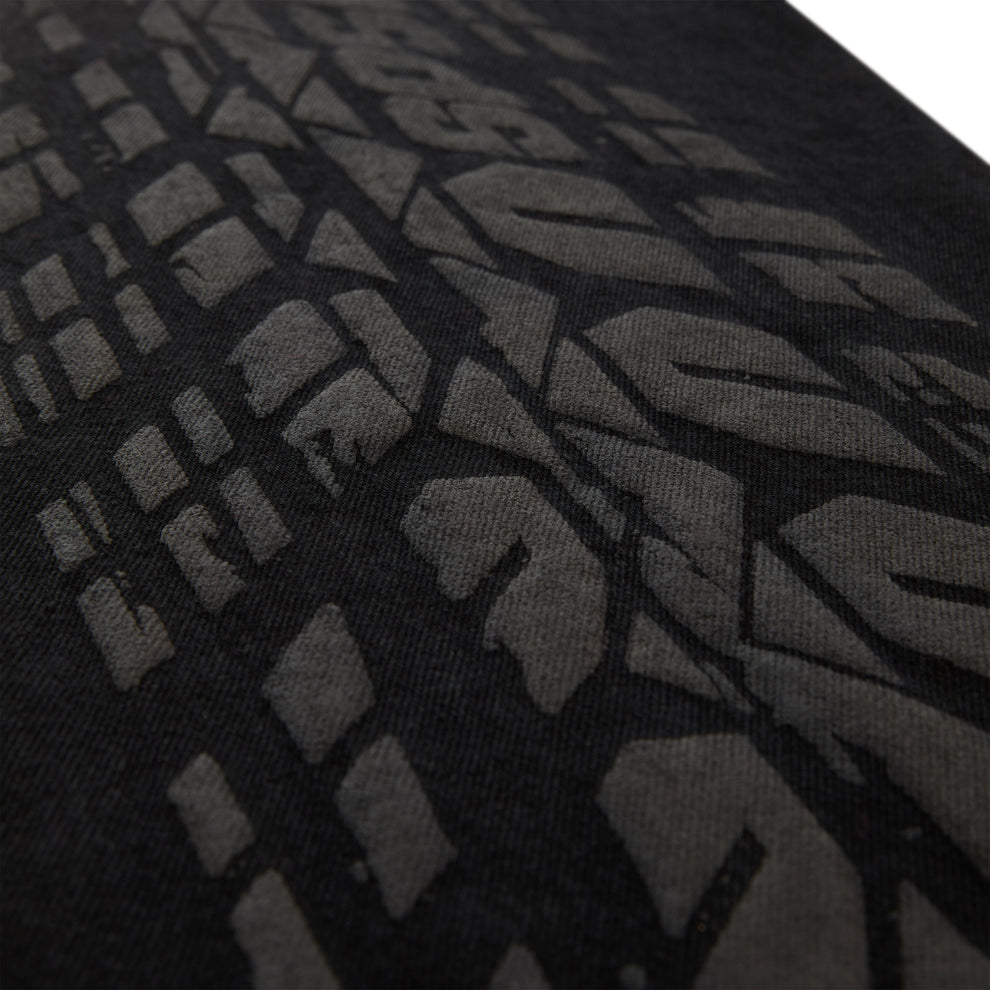 Close-up of black denim with an all-over dark gray tire track design.