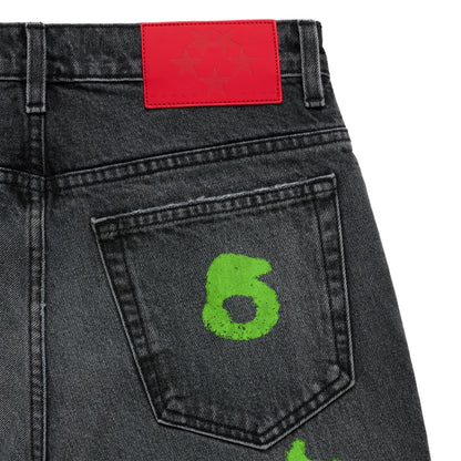 Faded wash black denim jeans with a bright red branded leather back patch and a neon green "6" stamp on the back pocket.