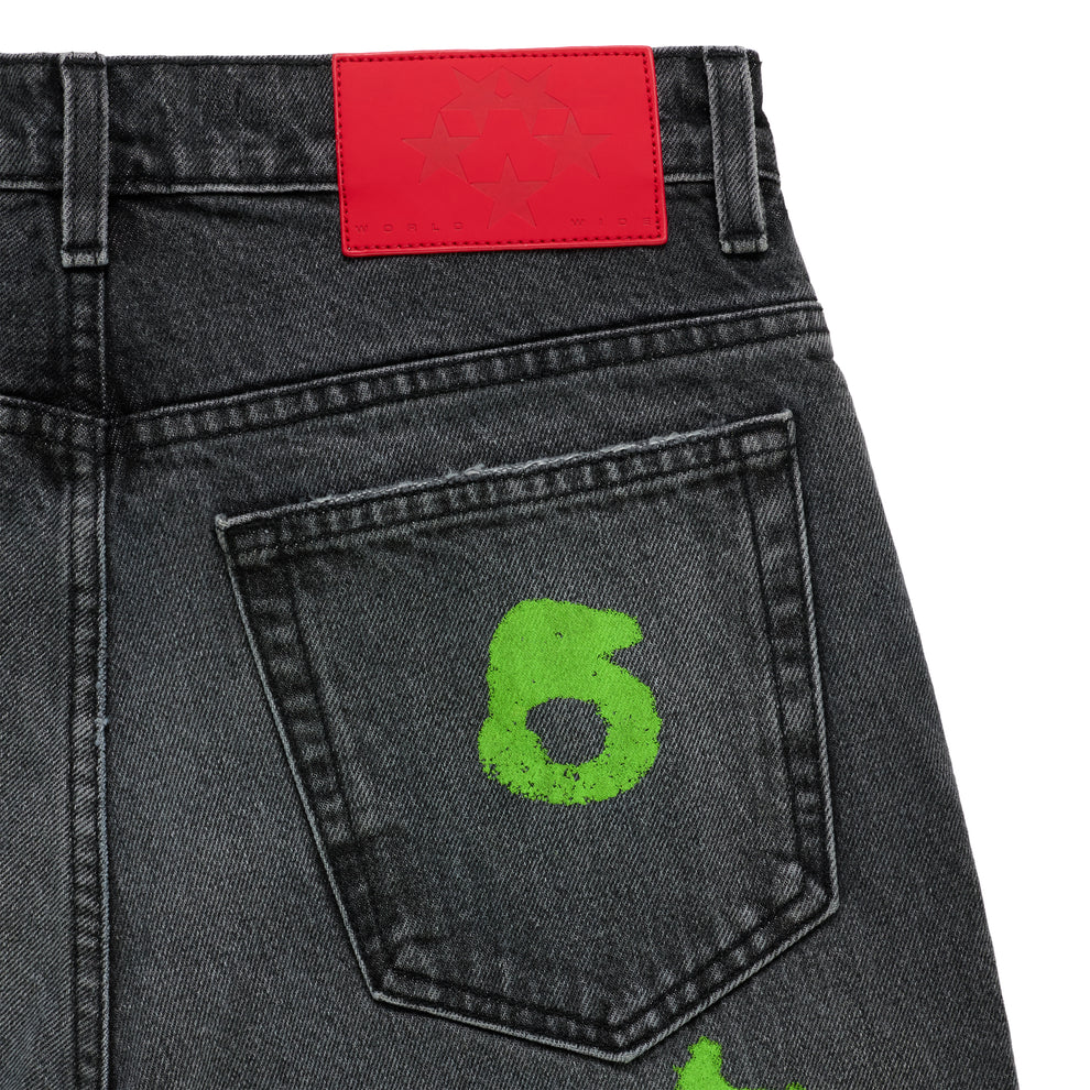 Faded wash black denim jeans with a bright red branded leather back patch and a neon green "6" stamp on the back pocket.